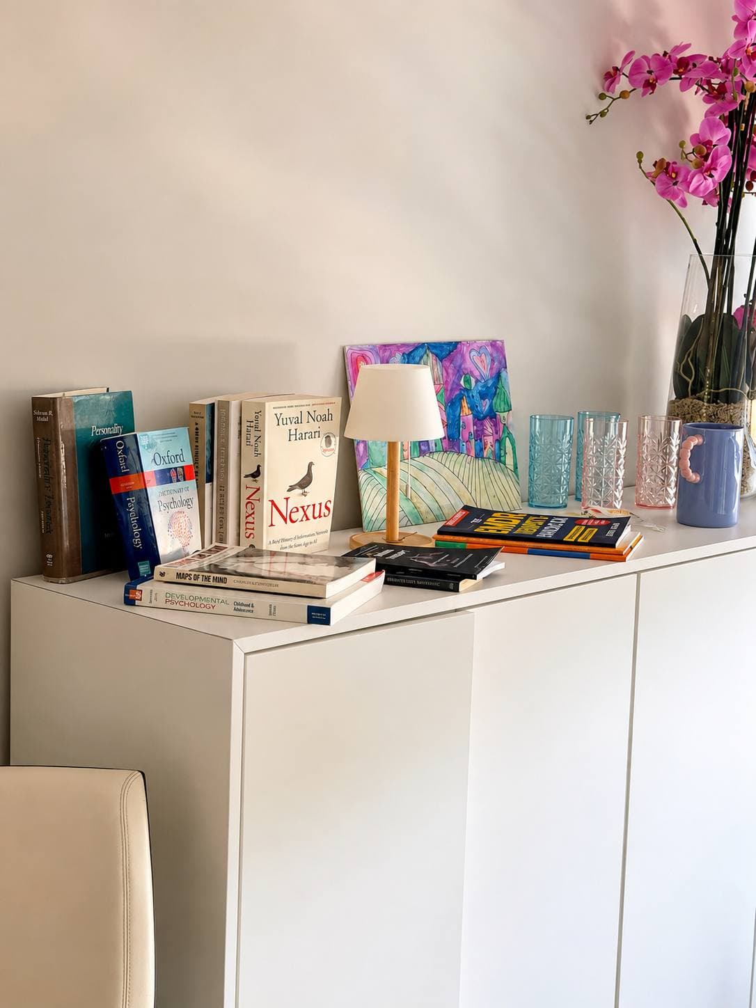 A shelf of psychology books, a table lamp and an orchid